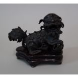 A Chinese bronze lion dog, Ming, modelled with its front right paw on a pierced ball, 85cm long,