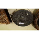 An old Thai 'nipple' gong, cast in relief two three dragons amidst scrolls, 23cm diameter.