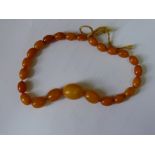 A 'butterscotch' amber bead necklace, of twenty four graduated oval beads, 16.3g.