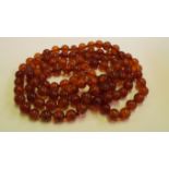An amber bead necklace, of 108 near spherical beads, each approx 10mm diameter, 188cm long, 219g.