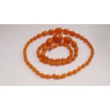Two similar amber style graduated oval bead necklaces,