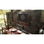 A Chinese carved hardwood side cabinet, Qing, the pair of doors inset with pierced panels,