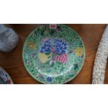 A Chinese famille rose dish, Qianlong seal mark, painted with flowers against a green ground, 25.5cm