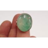 A yellow metal jadeite cabochon ring.