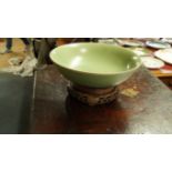 A Chinese celadon circular bowl, 29.5cm diameter, on hard wood stand.