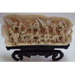 A Chinese carved ivory tusk section, late 19th century, carved in relief with seventeen figures,