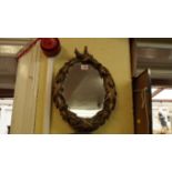 A carved gilt wood framed oval wall mirror, carved with leaves and berries, 37cm high.