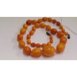 A 'butterscotch' amber bead necklace, of thirty-four graduated oval beads, 56cm long, 41g.
