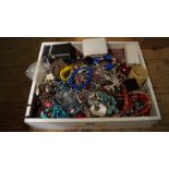 A wooden tray containing costume jewellery.