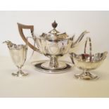 A late Victorian silver three piece tea set and teapot stand, by Thomas Bradbury & Sons Ltd,