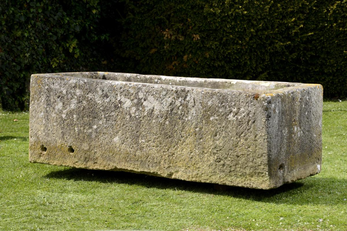 A large carved limestone trough  69cm.; 27ins high by 213cm.; 84ins long by 92cm.; 36ins deep