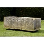 A large carved limestone trough  69cm.; 27ins high by 213cm.; 84ins long by 92cm.; 36ins deep
