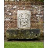 A carved stone wall fountain and trough  French, 19th century and earlier mouth drilled for water