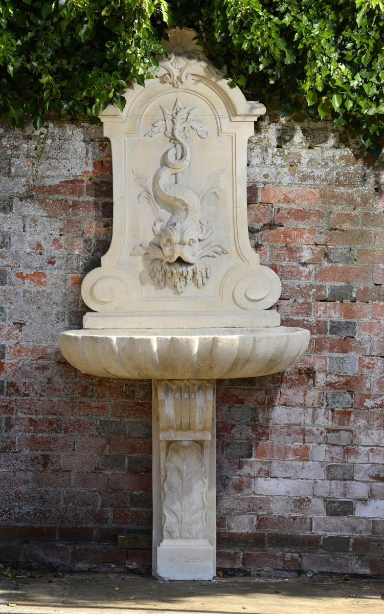 A Louis XVI style carved limestone wall fountain  late 19th century 228cm.; 90ins high by 100cm.;