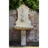 A Louis XVI style carved limestone wall fountain  late 19th century 228cm.; 90ins high by 100cm.;