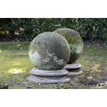 A pair of substantial carved stone gate pier balls  19th century on associated granite socles 74cm.;