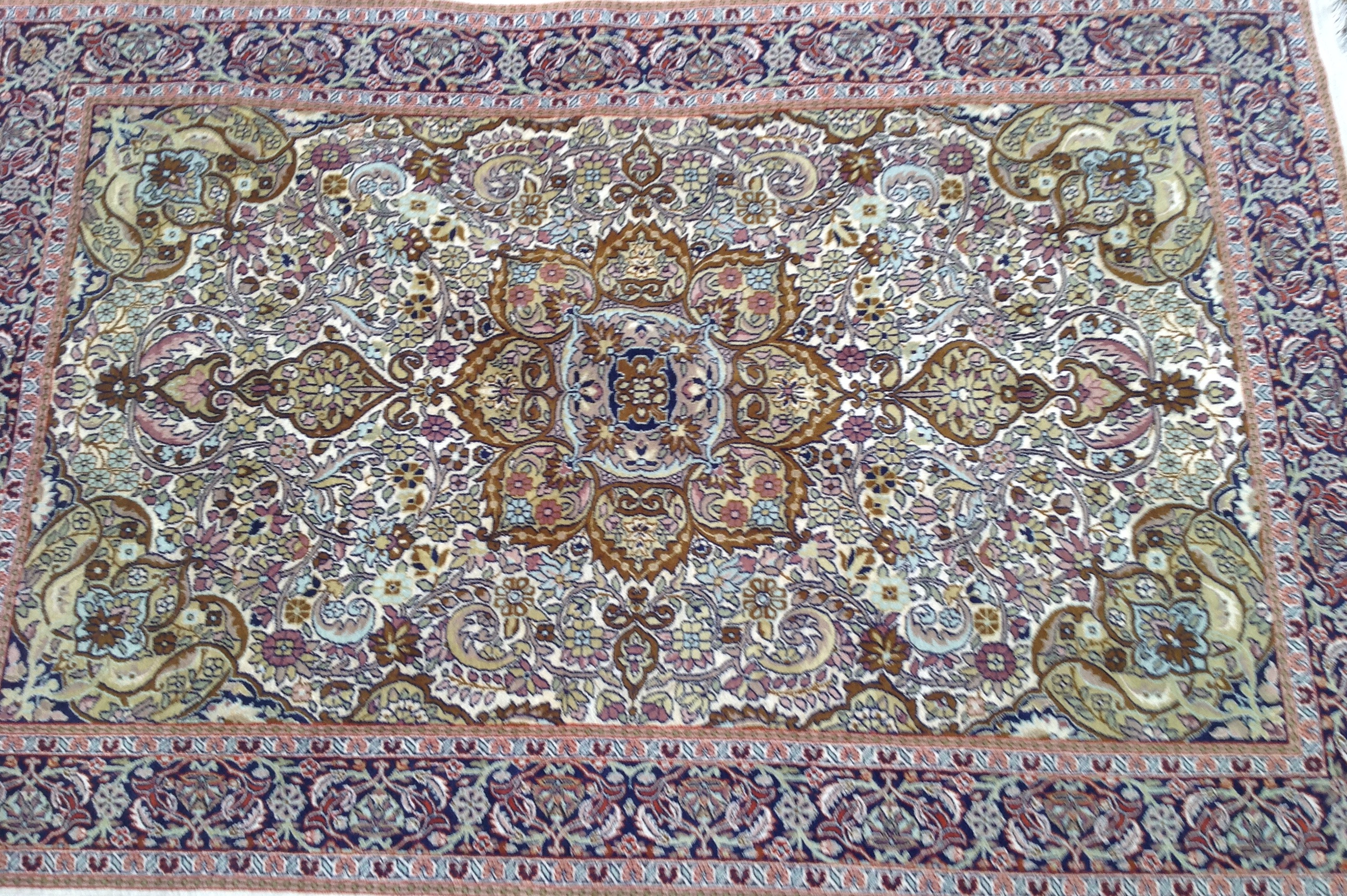 A 20TH CENTURY INDIAN RUG Having a cream field decorated with red borders and a stylized floral