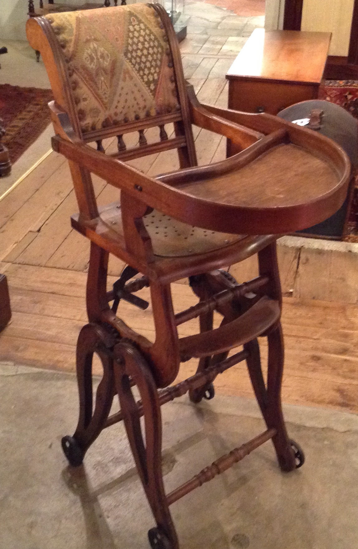 AN EDWARDIAN METAMORPHIC CHILD'S HIGH CHAIR Having beech wood on wheels and a decorative fabric