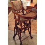 AN EDWARDIAN METAMORPHIC CHILD'S HIGH CHAIR Having beech wood on wheels and a decorative fabric