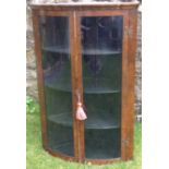 AN EARLY 19TH CENTURY MAHOGANY BOW FRONTED WALL HANGING CORNER CABINET With two glazed doors