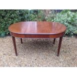 AN EDWARDIAN MAHOGANY OVAL EXTENDING DINING TABLE  With one extra leaf and raised on square tapering