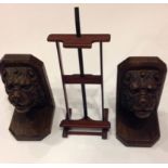 A PAIR OF CARVED OAK BOOKENDS In the form of lion masks, along with a miniature picture easel.
