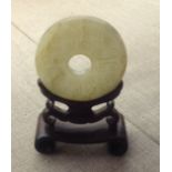 AN ANTIQUE CHINESE PALE JADE BI Raised on a hardwood stand.