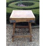 AN EARLY 20TH CENTURY PINE BUTCHERS BLOCK  With steel corner brackets and raised on four splayed