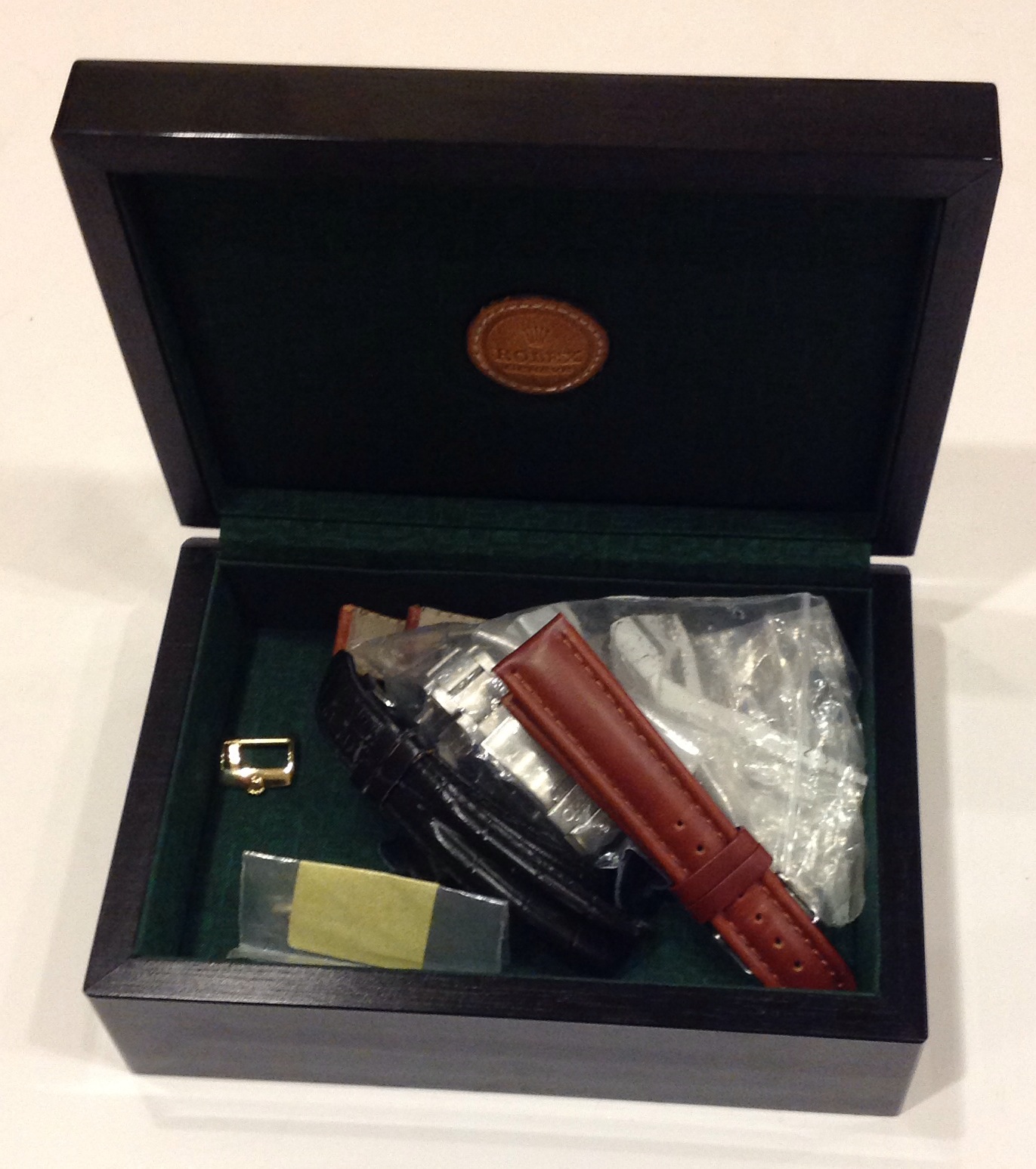 A ROLEX WATCH BOX Containing leather straps, links and a yellow metal Rolex strap buckle.