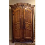 AN 18TH CENTURY FRENCH FRUITWOOD ARMOIRE  The hump top cornice above a floral basket and ogee