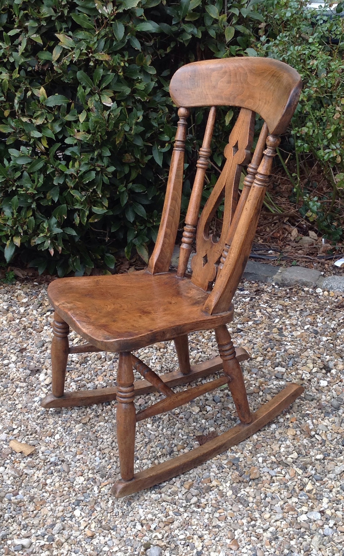 A VICTORIAN ASH AND ELM ROCKING CHAIR  Having a pierced splat back and supported on turned Roman