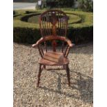 A 19TH CENTURY OAK, ELM AND YEW WINDSOR ARMCHAIR With Roman spindle rails and raised on turned legs,