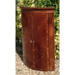 AN 18TH CENTURY MAHOGANY AND ROSEWOOD BOW FRONTED CORNER CUPBOARD The two doors having rosewood