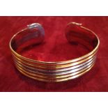 AN 18CT YELLOW AND WHITE GOLD RIBBED BANGLE Each end having a stylized 'C' and bearing hallmarks,