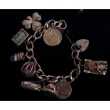 A FINE 9CT GOLD CHARM BRACELET  Hung with ten charms, to include a hinged caged dice, a hinged