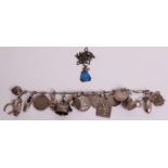 A SILVER CHARM BRACELET  Hung with eighteen charms, to include 20th Century coins, one being an 1852