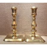 A PAIR OF GEORGE II BRASS CANDLESTICKS With petal form bases and square stepped knops. (approx