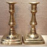 A PAIR OF 19TH CENTURY BRASS CANDLESTICKS  With ejector pusher, raised on rectangular stepped bases.