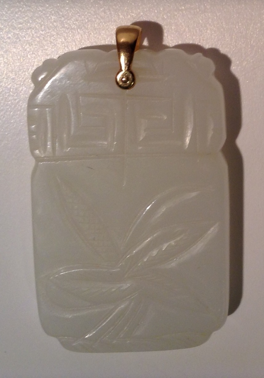 A WHITE JADE TABLET FORM PENDANT Decorated to each side with stylized flora, below a Greek Key