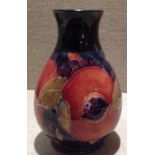 MOORCROFT, AN EARLY 20TH CENTURY SMALL BALUSTER VASE In pomegranate pattern on a blue ground,