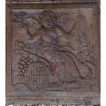 AN 18TH CENTURY FRENCH CARVED WALNUT PANEL Depicting a winged cherub seated on a wine barrel, with