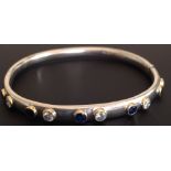 A 9CT WHITE GOLD, TEN STONE DIAMOND AND SAPPHIRE HINGE BANGLE The stones brilliant round cut, set in