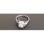 AN 18CT GOLD RING SET WITH ROUND CUT DIAMOND SOLITAIRE In a square mount, each shoulder set with