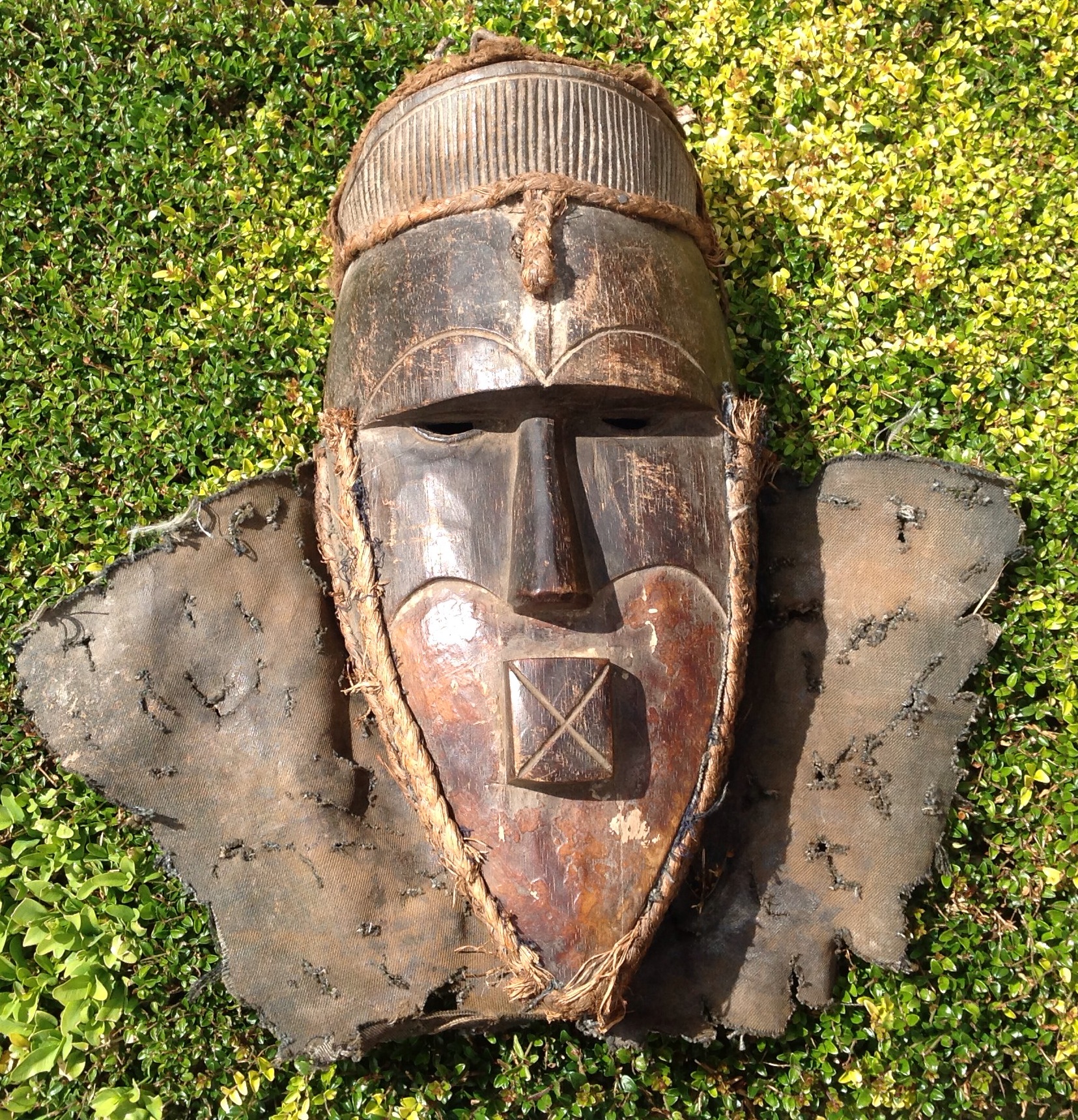 A CARVED AFRICAN TRIBAL ART SONGYE WOODEN MASK Having carved eyebrows and a protruding square mouth,