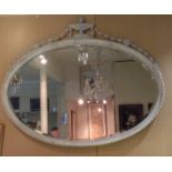 A LARGE EARLY 20TH CENTURY OVAL BEVELLED PLATE MIRROR The weathered painted frame, mounted with an