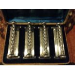 A SET 19TH CENTURY SILVER PLATED KNIFE RESTS  With a rope twist bar, mounted on rectangular plinths,