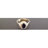 AN 18CT GOLD, SAPPHIRE AND DIAMOND RING The oval brilliant cut sapphire within a border of small