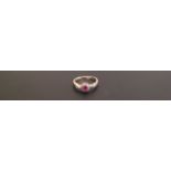 A 9CT GOLD, RUBY AND DIAMOND RING The oval brilliant cut ruby within a surround of small round cut