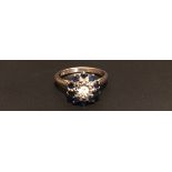 AN 18CT WHITE GOLD, SAPPHIRE AND DIAMOND CLUSTER DRESS RING The central round cut diamond illusion