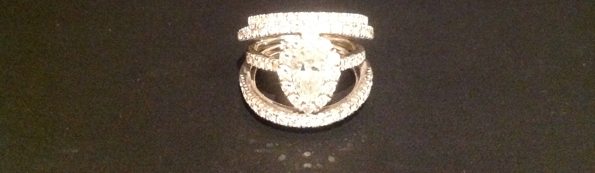 AN 18CT WHITE GOLD AND DIAMOND DRESS RING The central pear cut diamond, contained in a border of